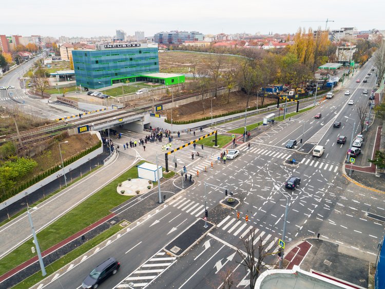 Make new from old. Photo: Aerial view of the finalised bridge branded with PORR banners next to a crossing of two frequented roads with four to five lanes each; the road section under the bridge is still closed with a group of people waiting for the opening ceremony of the bridge.