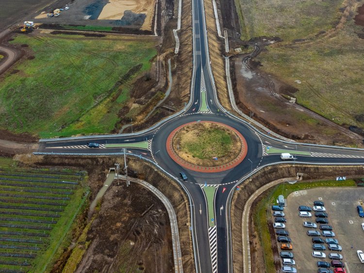 Optimisation of the traffic flow A slight bird's eye view of a road under construction. In the foreground you can see a newly constructed roundabout, in the background a bridge leads over a railway line.